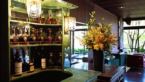 A bar area with shelves of liquor bottles, a large vase with flowers, and a view of the outdoors through a window. - Hana No Shizuku (Ureshino)