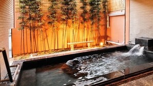 A hot spring area with a bench, bamboo wall, and a water feature. - Hana No Shizuku (Ureshino)