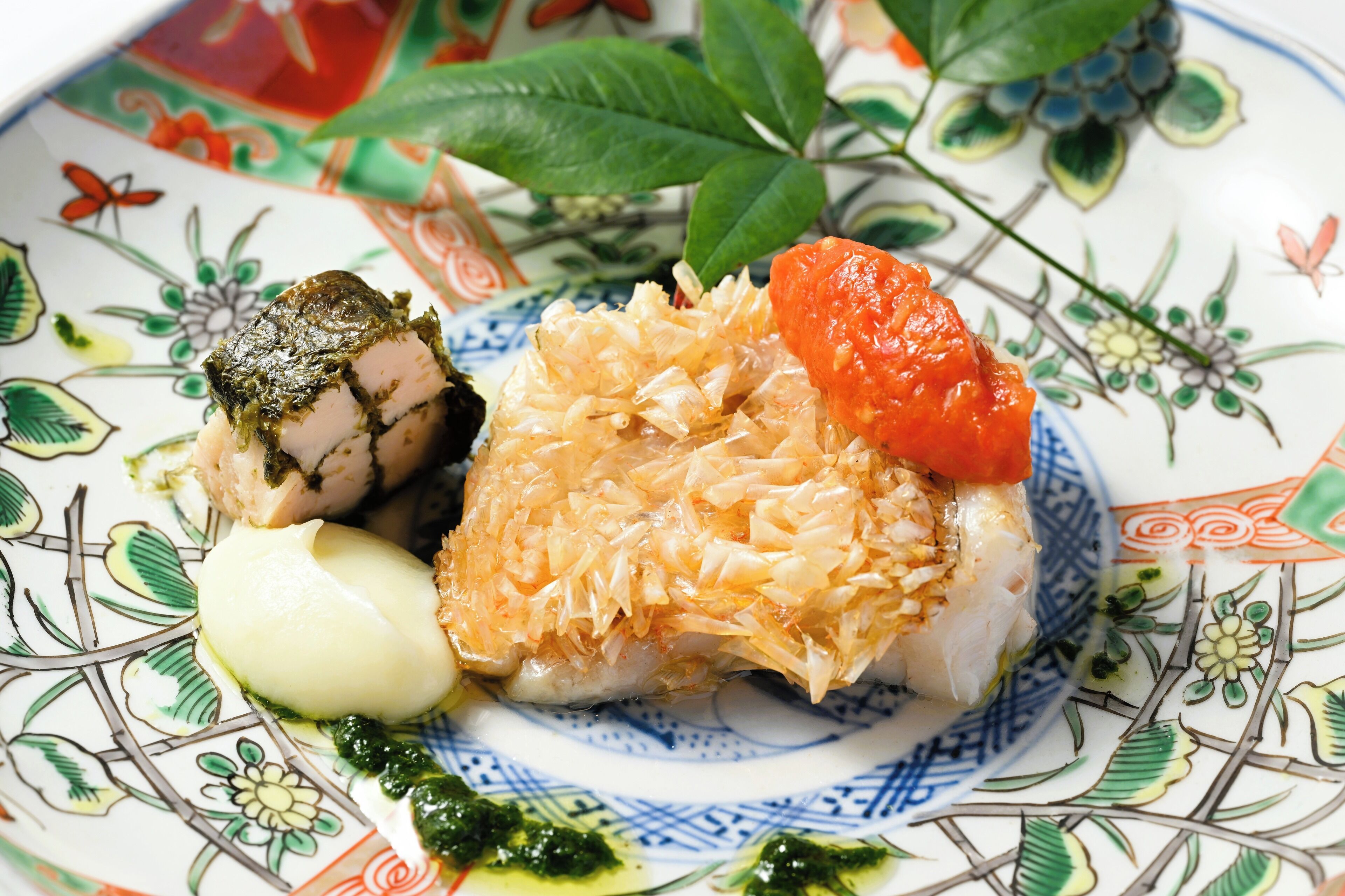 A plate with sushi, a piece of fish topped with seaweed, and a slice of fish covered in shredded topping.