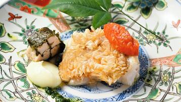 A plate with sushi, a piece of fish topped with seaweed, and a slice of fish covered in shredded topping.