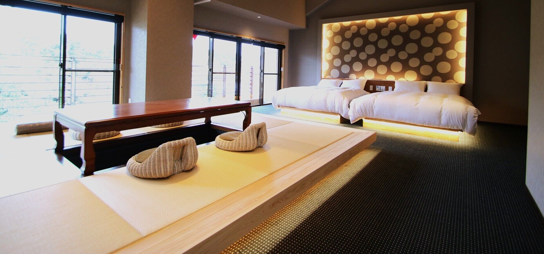 A hotel room with a large bed, a wooden table, and a massage table.