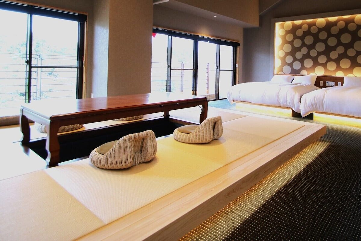 A hotel room with a large bed, a wooden table, and a massage table.
