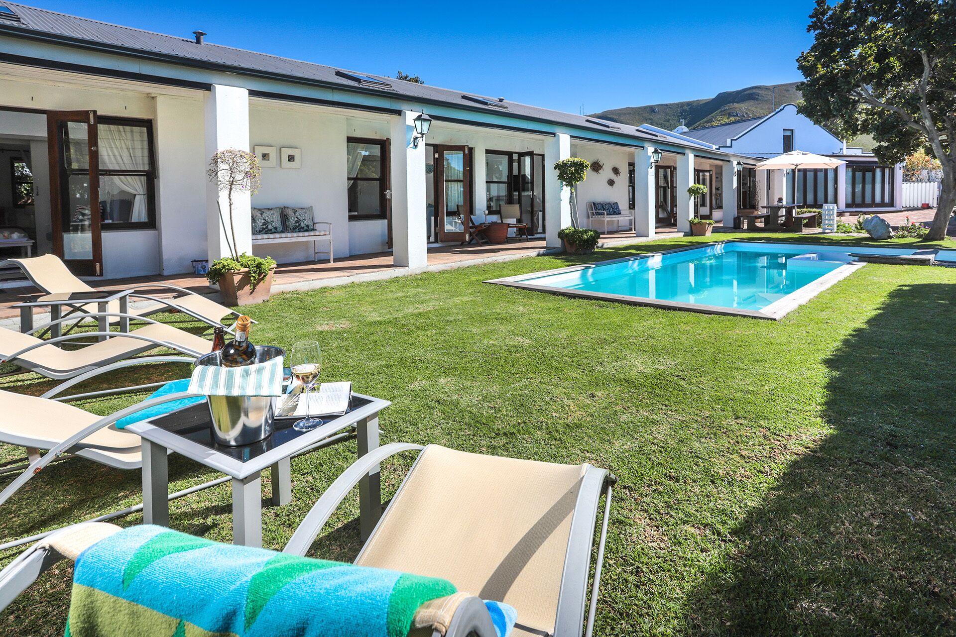 Un espace aménagé au bord de la piscine, avec des chaises longues, une table sur laquelle se trouvent une bouteille et un verre, et une vue dégagée sur la piscine.