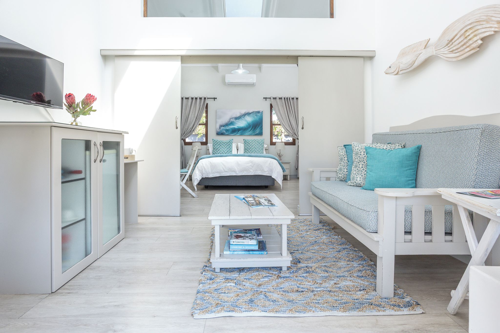 Una habitación moderna y bien iluminada con cama, sofá, mesa de centro y televisor.