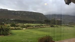 En golfbane med udsigt til bjerge og en skyet himmel.