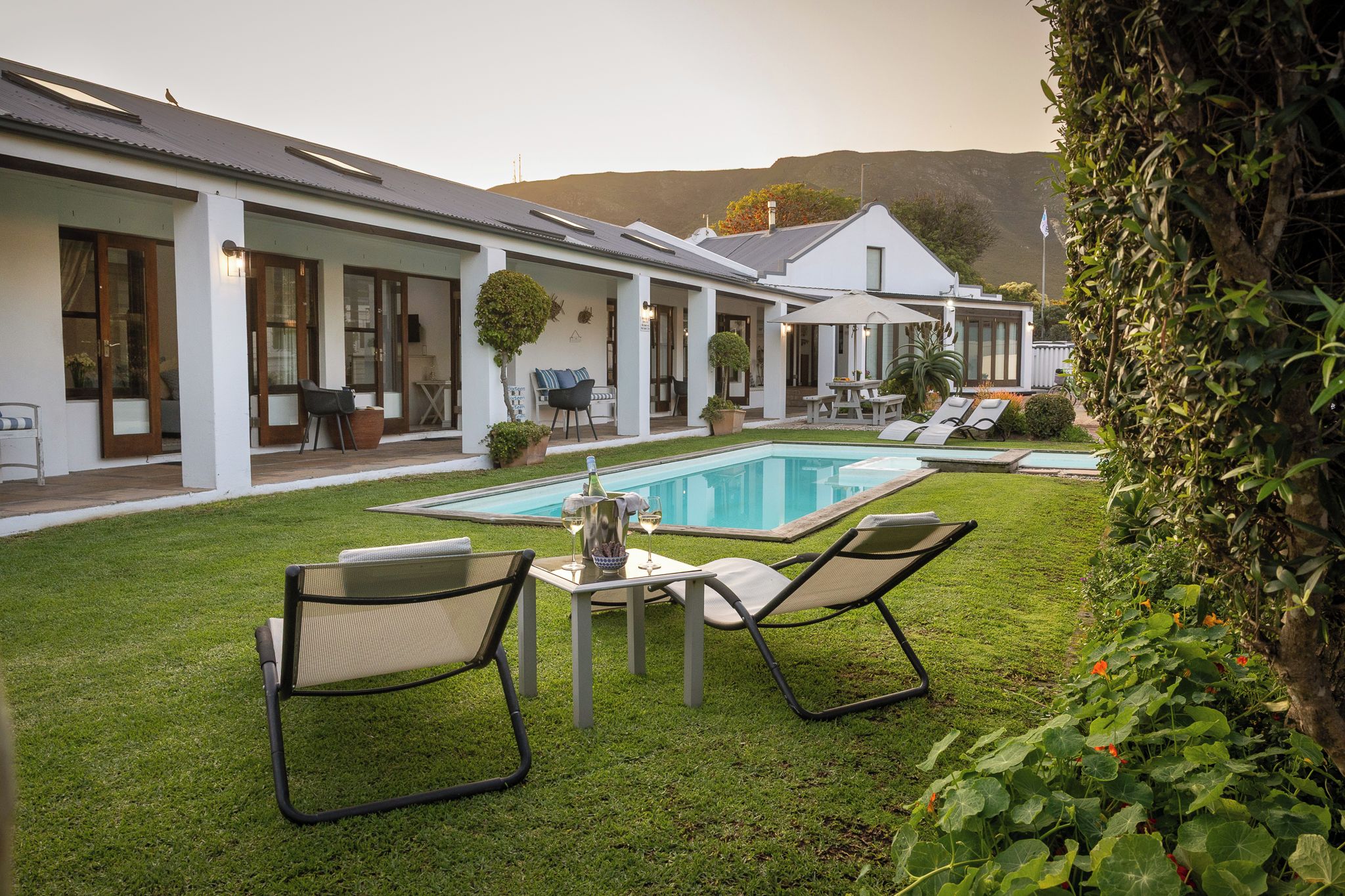 A modern house with a swimming pool, outdoor seating, and a view of hills.