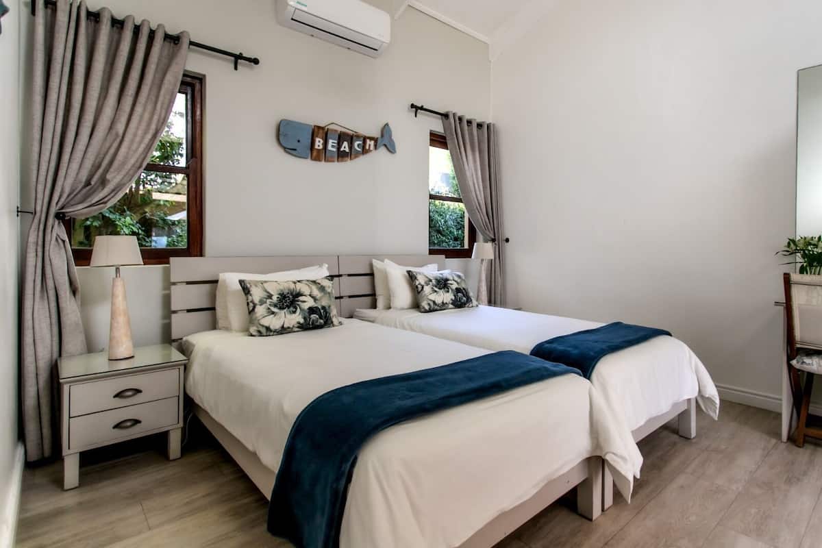 A bedroom with two beds, a nightstand, a lamp, and a wall decoration.
