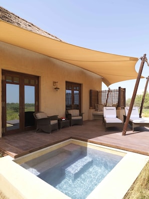A pool area with a hot tub, outdoor seating, and a covered patio.
