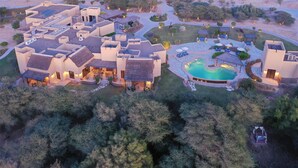 An aerial view of a resort with multiple buildings, a swimming pool, and landscaped gardens.