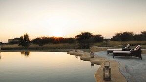 Zona de piscina exterior tranquil·la amb gandules i fanalets, envoltada per un paisatge natural i un tramunt.