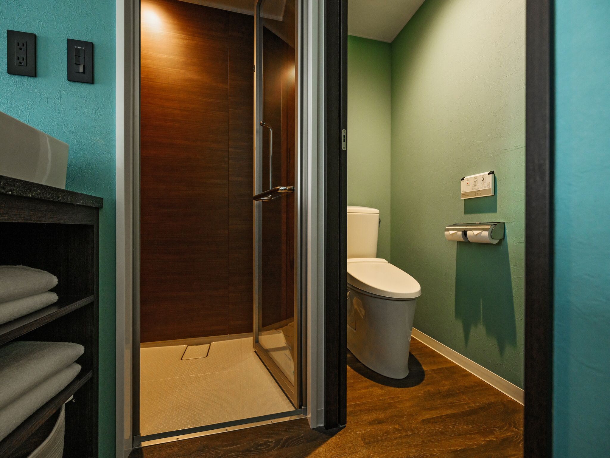 A bathroom with a glass shower door, a toilet, and a towel rack.