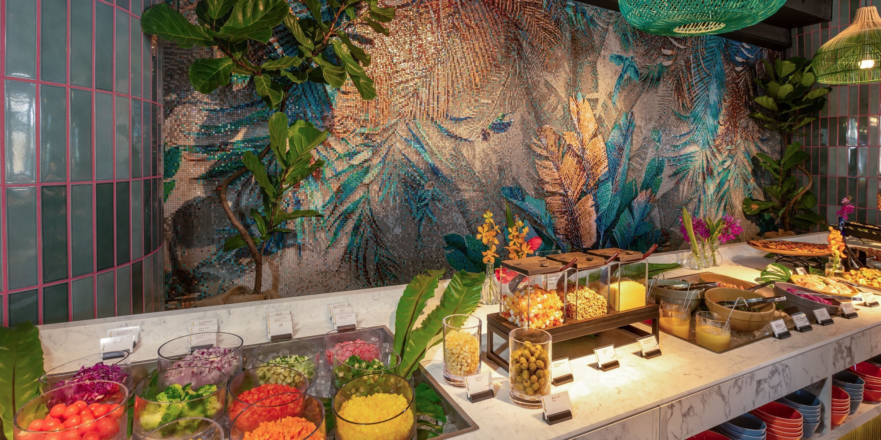 A buffet with various food items and a decorative wall with a mosaic pattern.
