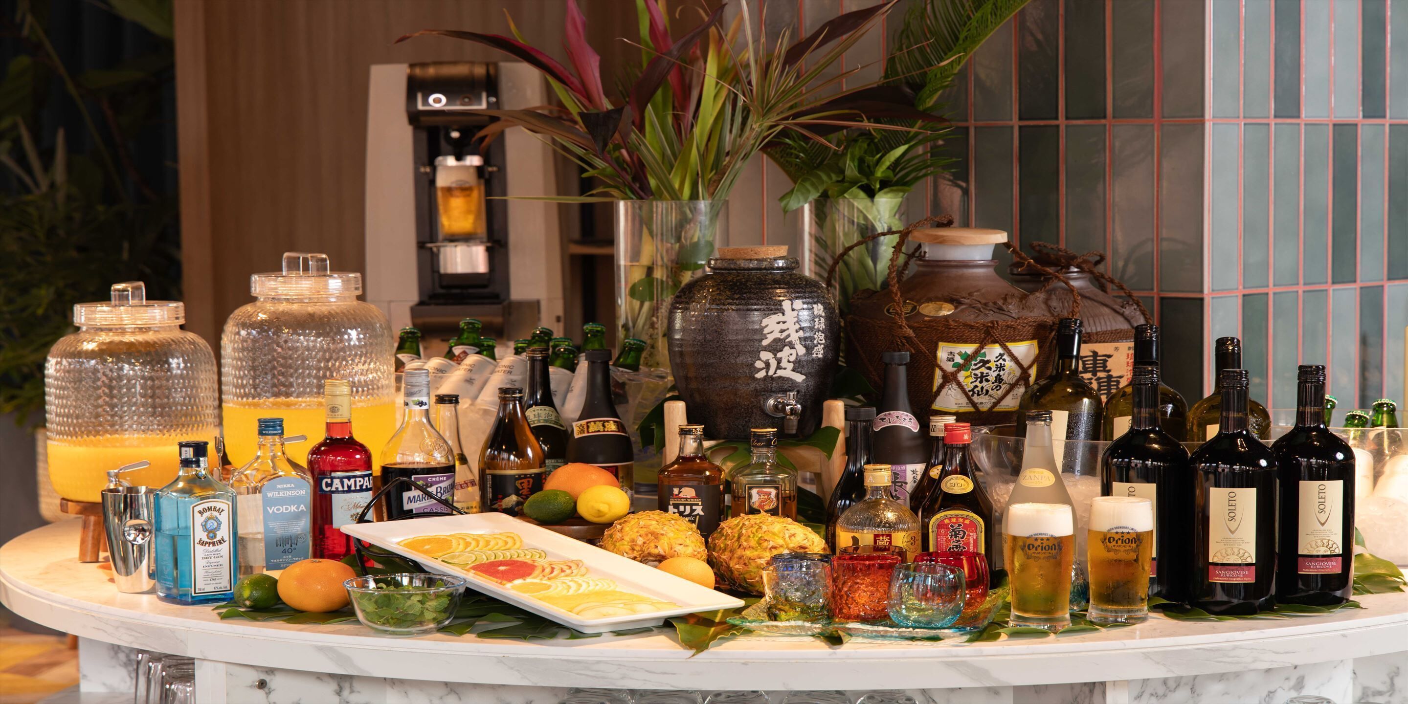 Eine Bar mit verschiedenen Alkoholflaschen, Gläsern und einer Obstplatte.