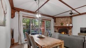 A cozy living room with a fireplace, a dining table with chairs, and a grey sofa.