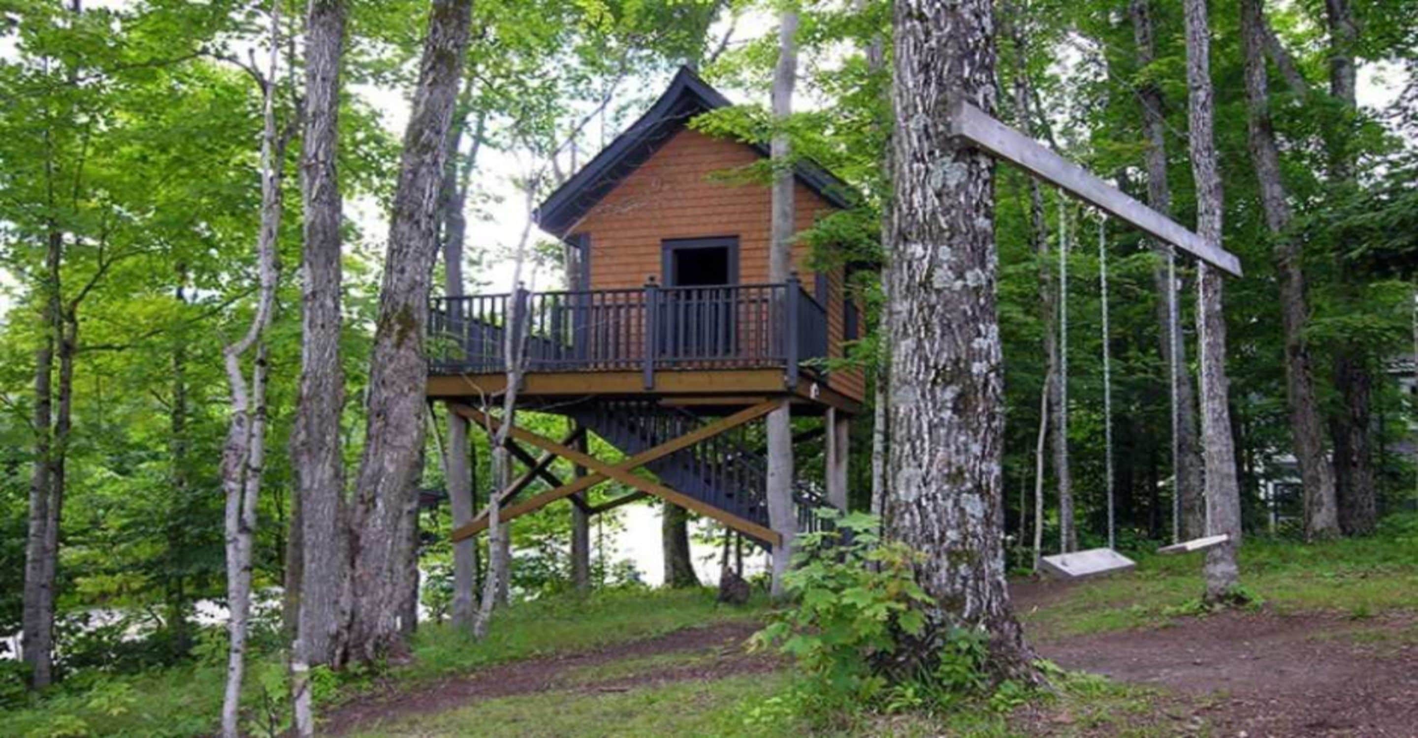 A wooden cabin with a balcony, surrounded by trees.
