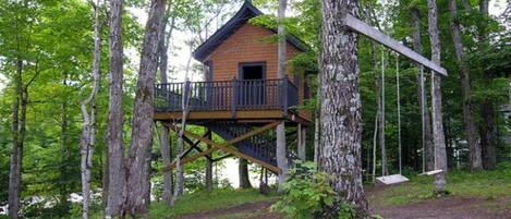 A wooden cabin with a balcony, surrounded by trees.