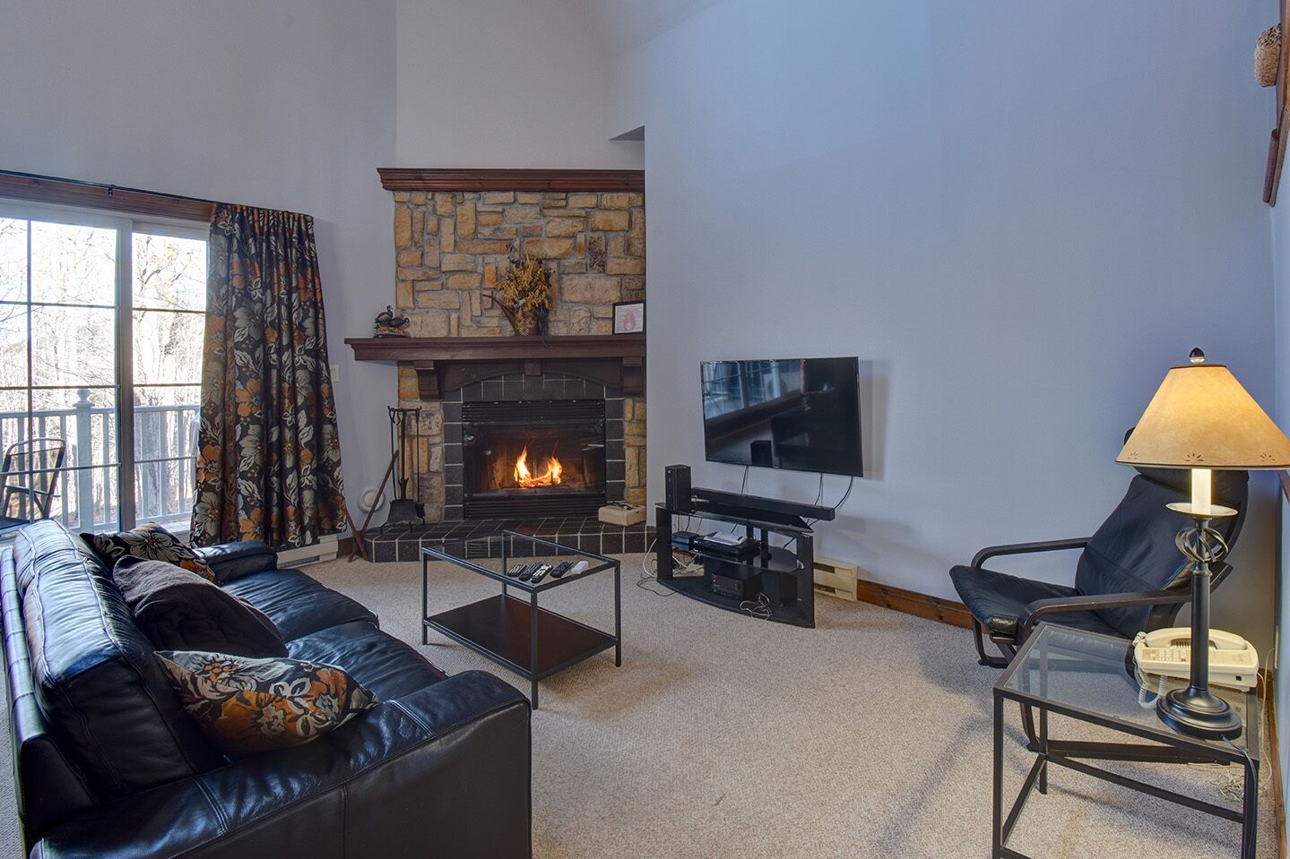 Ein Wohnzimmer mit Kamin aus Stein, einem Fernseher, einer Couch, einem Couchtisch und einem Sessel.