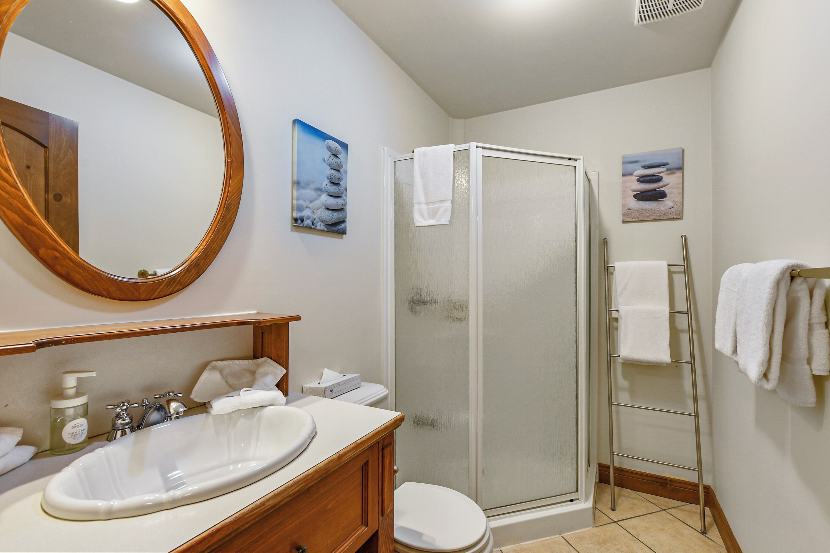 Une salle de bain avec un meuble-lavabo en bois, un grand miroir, une cabine de douche et deux porte-serviettes fixés au mur.