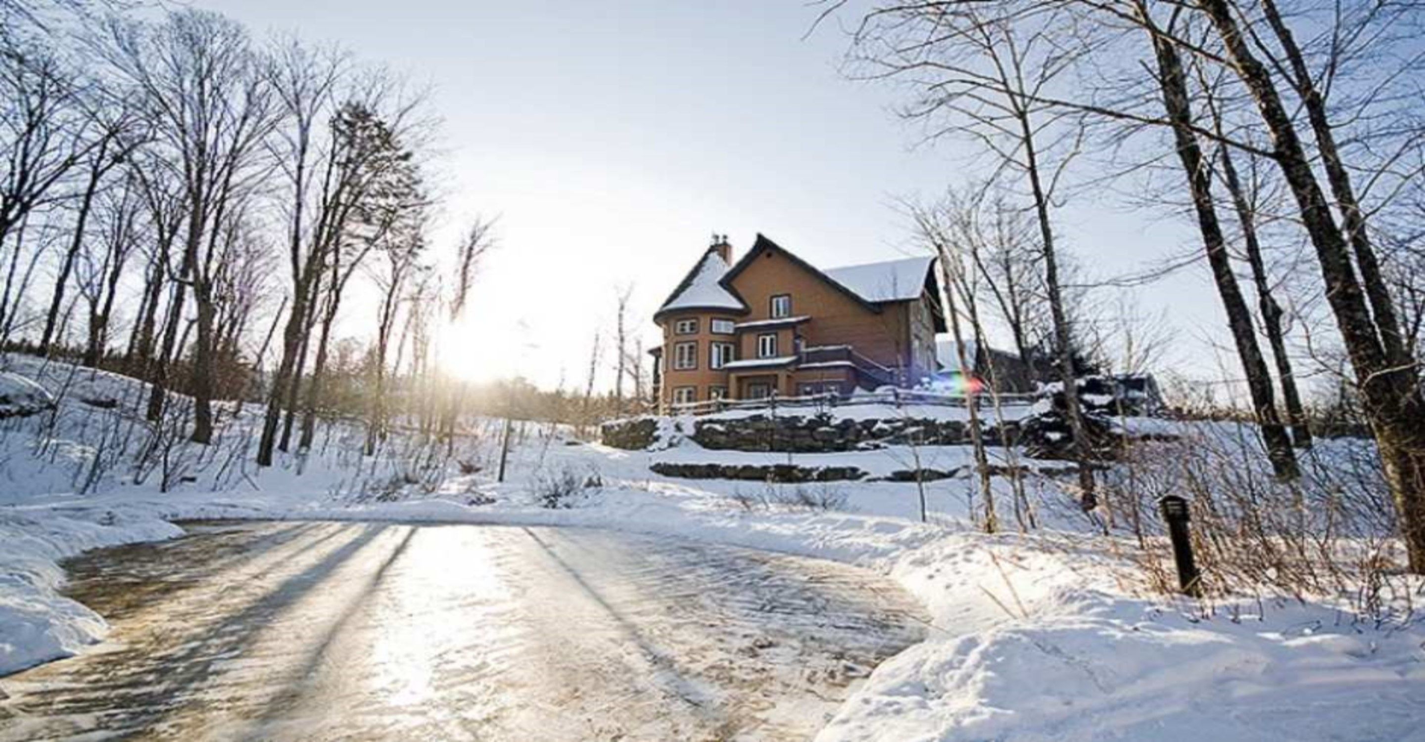 A snow-covered landscape with a house and a road.