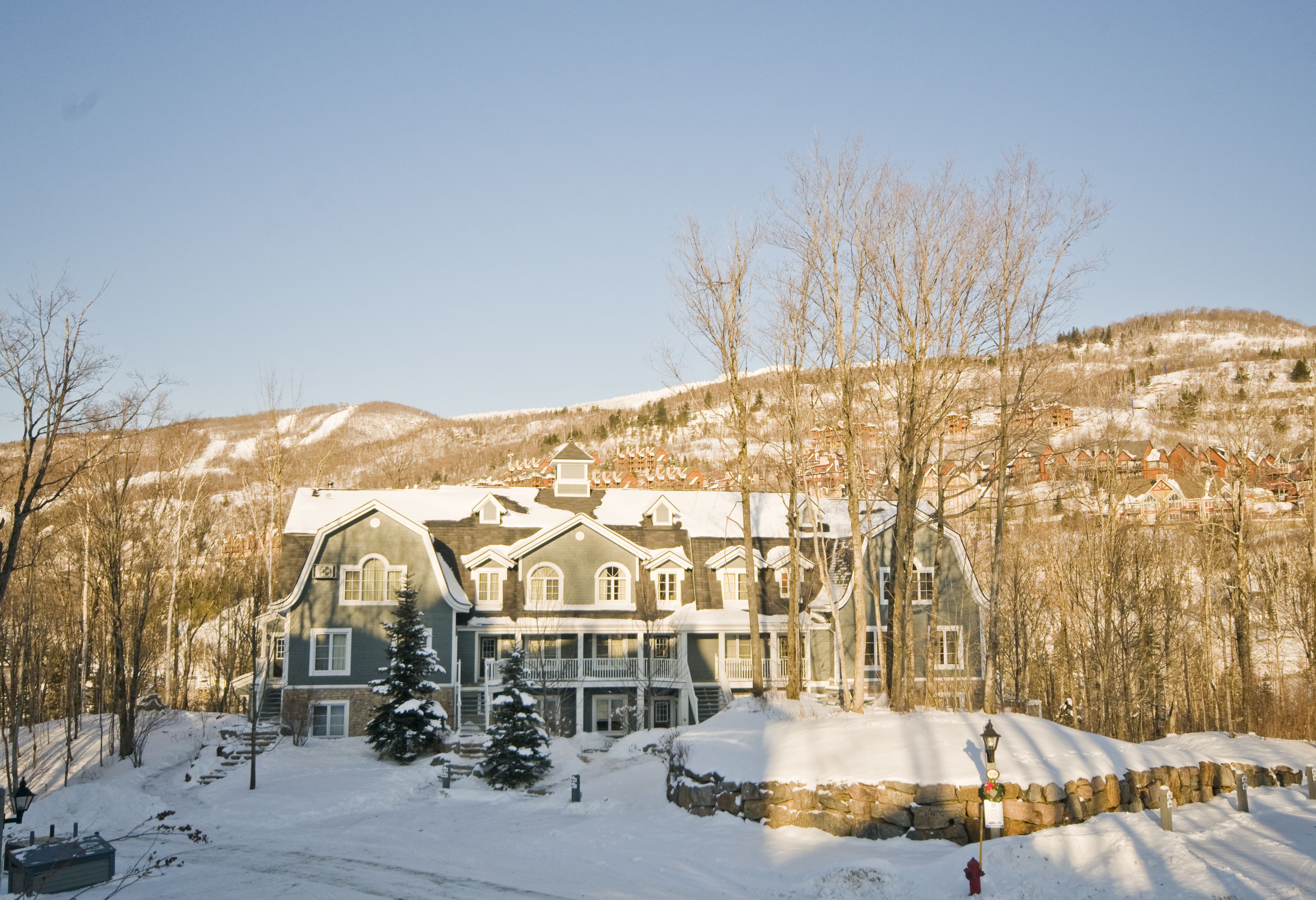 A large, multi-story building with a prominent entrance and a balcony, surrounded by snow-covered landscape and trees.