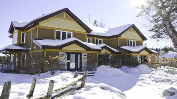 A large two-story house with a covered porch and a snow-covered roof. - L'Aiglon - RVMT (Mont-Tremblant)