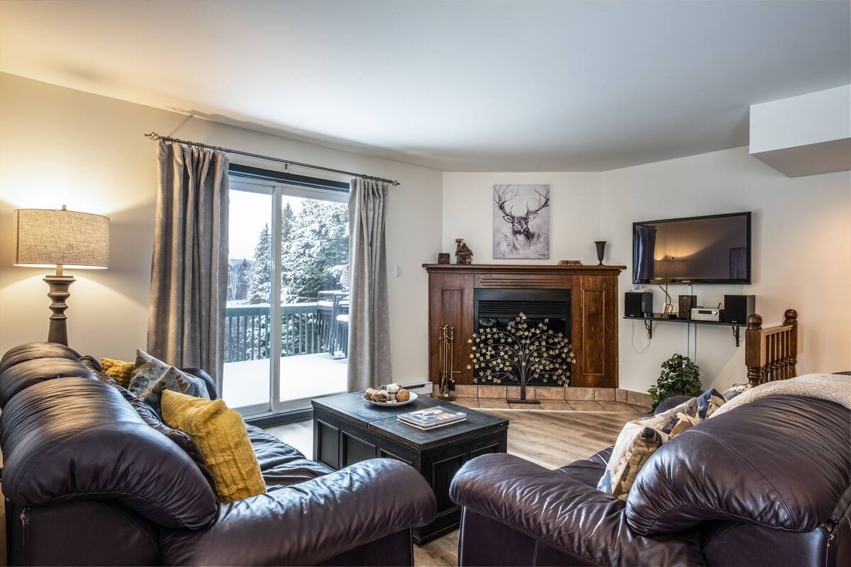 Ein Wohnzimmer mit Kamin, Ledersofas, einem Couchtisch und einem Fernseher.