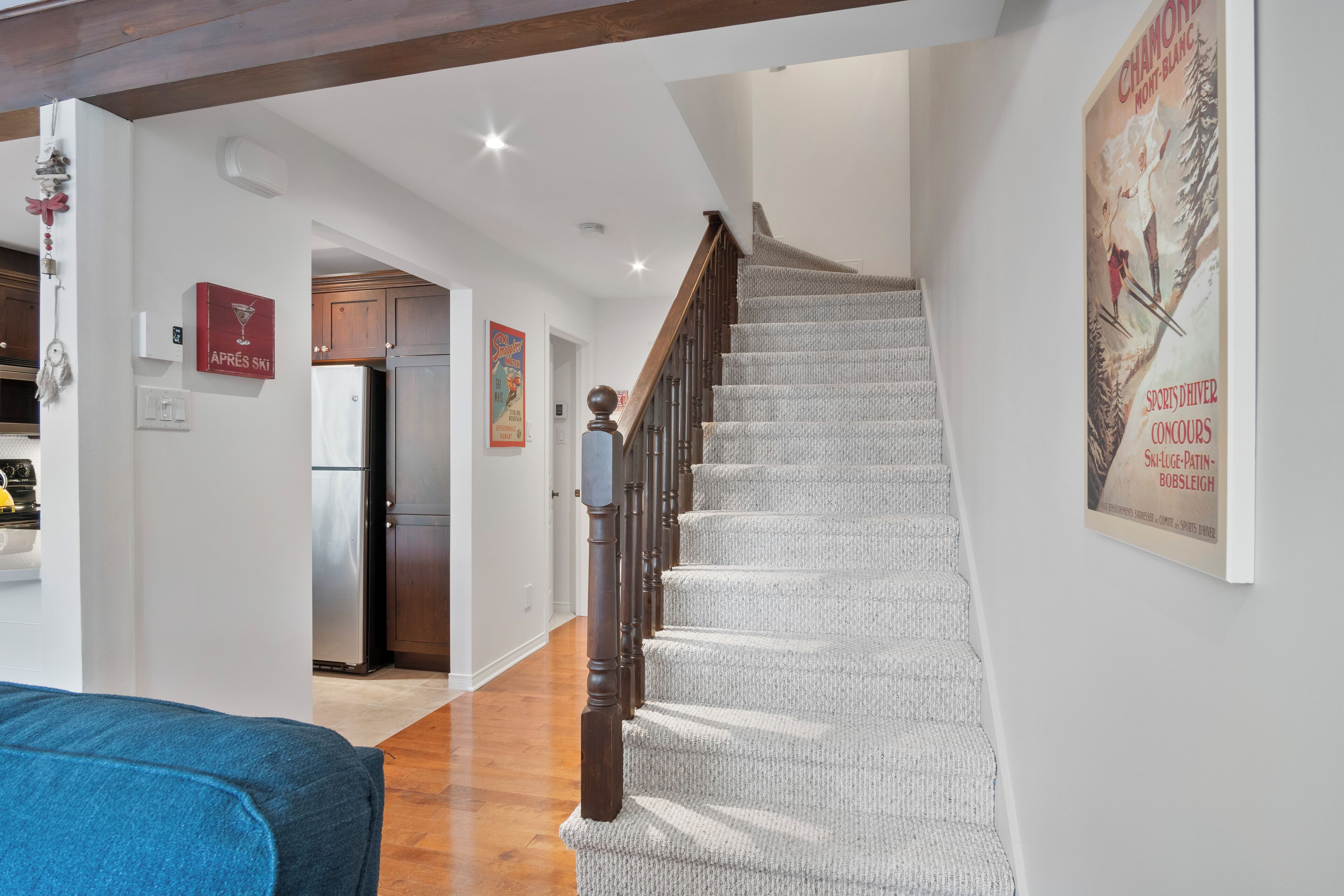 A staircase with a wooden handrail leading to a landing. A poster is visible on the wall to the right.