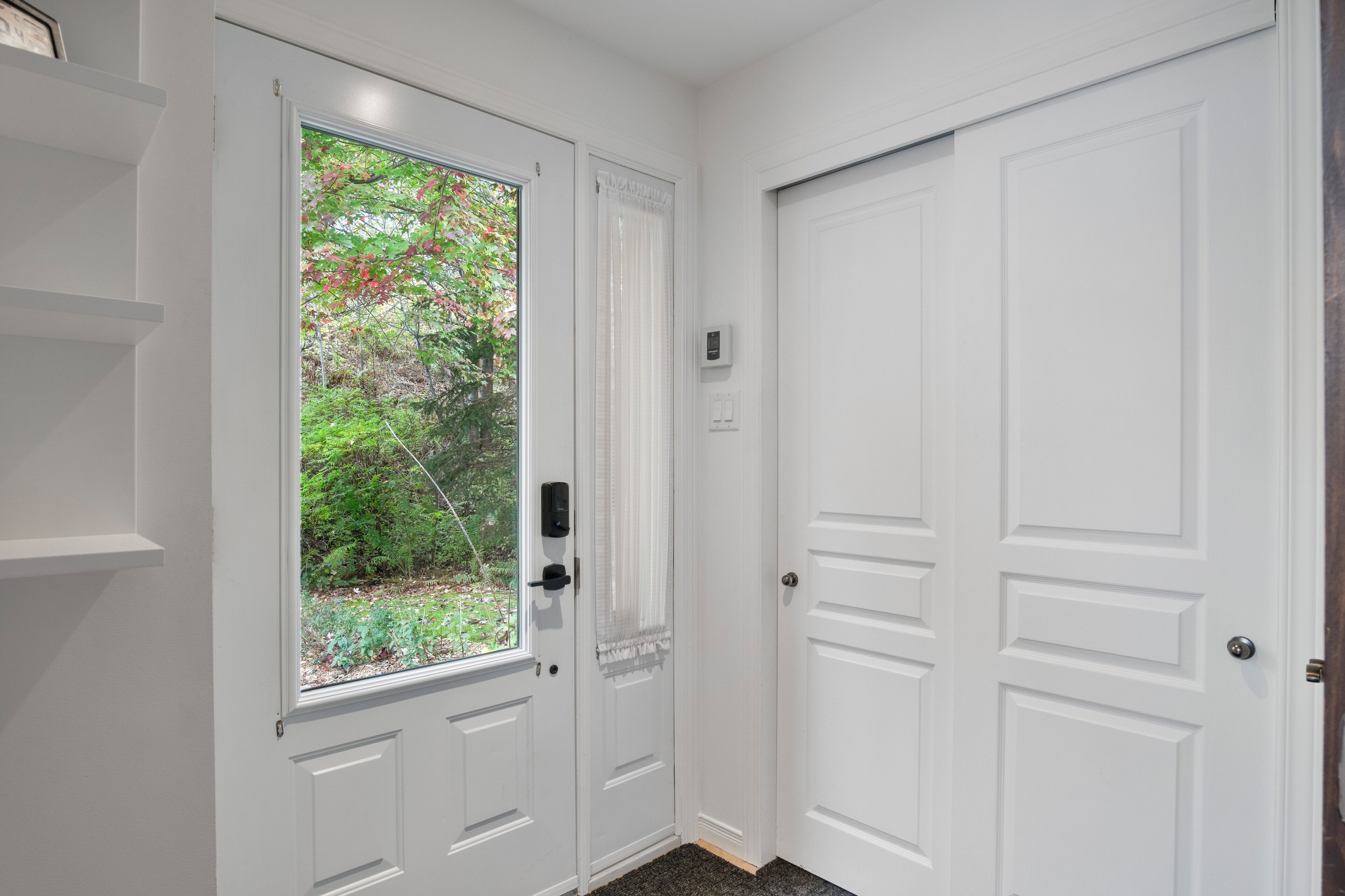A white door with a window, a doorbell, and a thermostat.