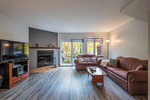 A modern living room with a flat-screen TV, a fireplace, a sofa, and a coffee table.