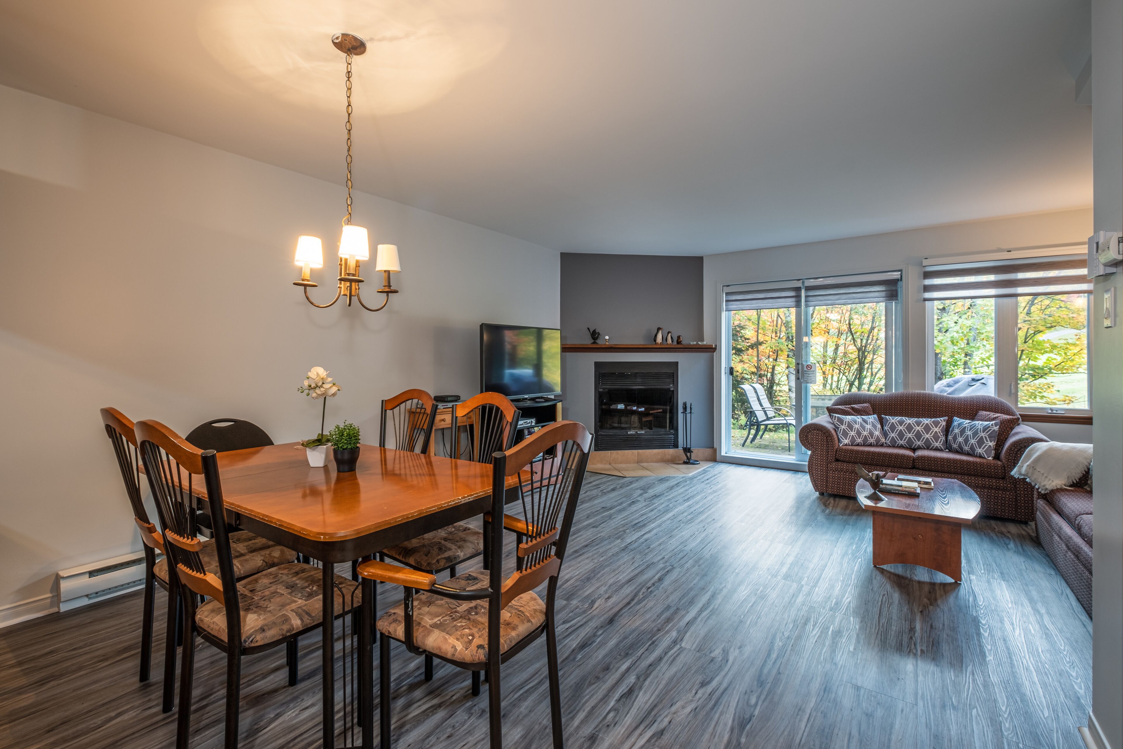 A modern living room with a dining table, chairs, a sofa, and a fireplace.