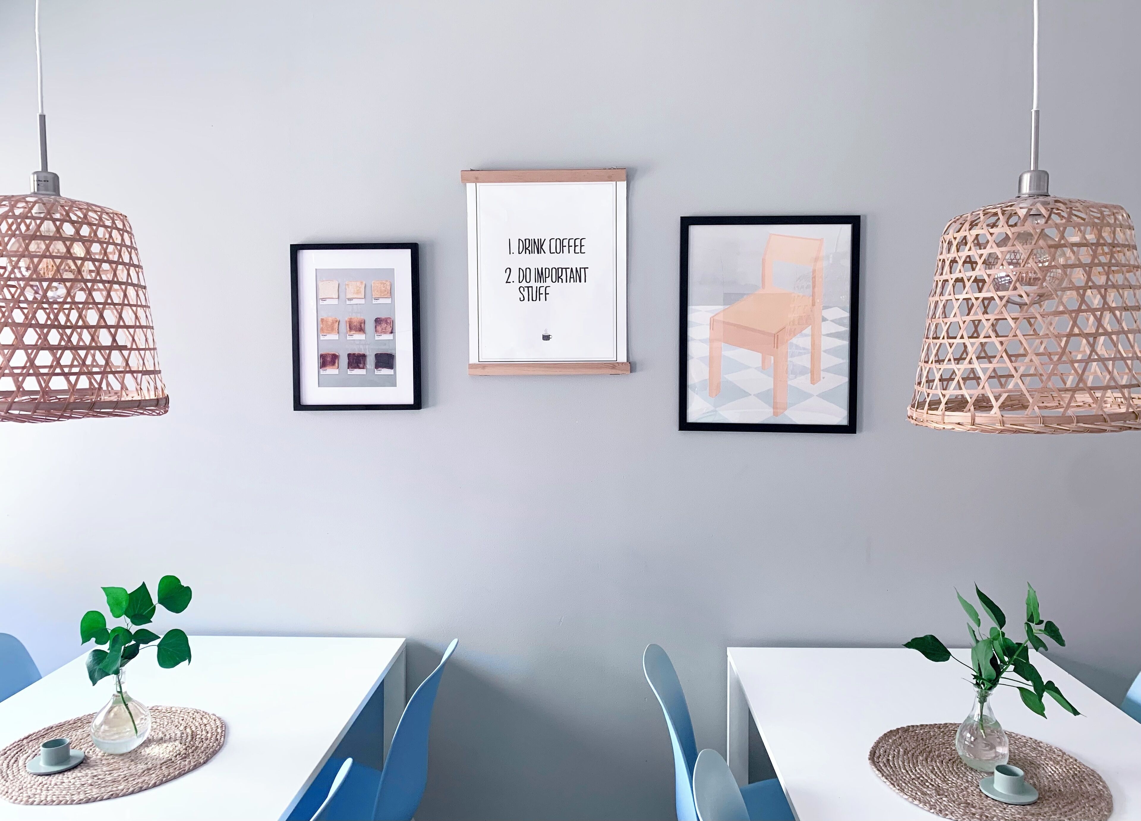 Een moderne eethoek met twee tafels, blauwe stoelen en hangende wilgenpendels.