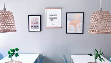 Een moderne eethoek met twee tafels, blauwe stoelen en hangende wilgenpendels.