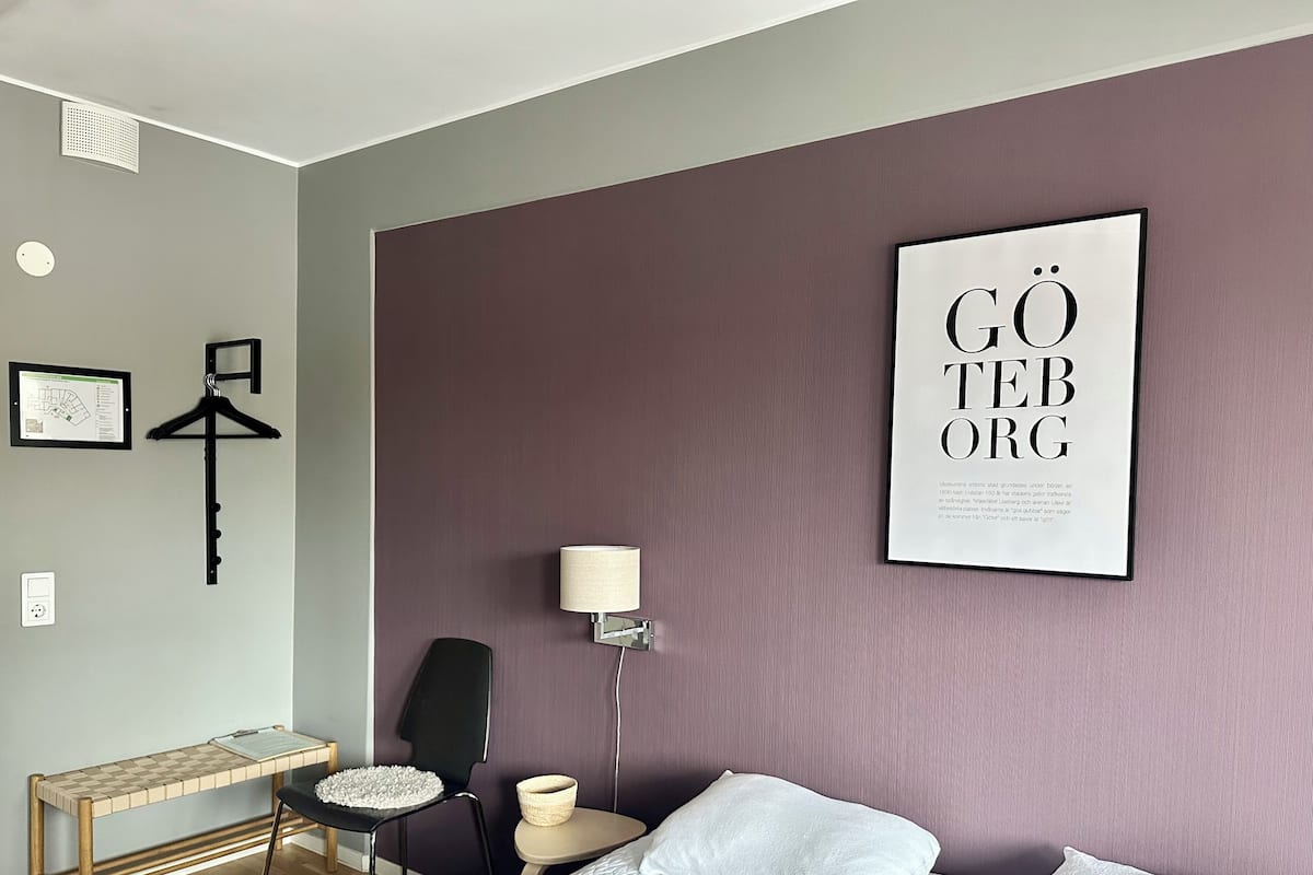 Ein Hotelzimmer mit Bett, Schreibtisch, Stuhl, Lampe und einem gerahmten Poster an der Wand.