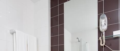 A modern bathroom with a white bathtub, a pedestal sink, and a large mirror.