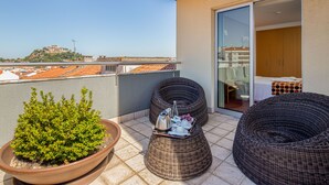 A balcony with wicker furniture, a potted plant, and a table with bottles and glasses. - Stay Hotel Leiria Centro (Leiria)