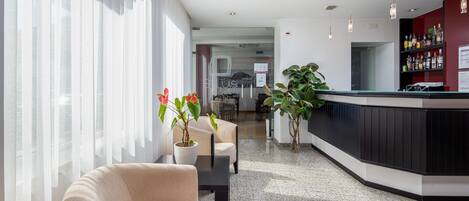 Un vestíbulo moderno con área de descanso, recepción y bar.