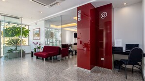 A modern reception area with a red desk, black chairs, and a glass partition. - Stay Hotel Leiria Centro (Leiria)