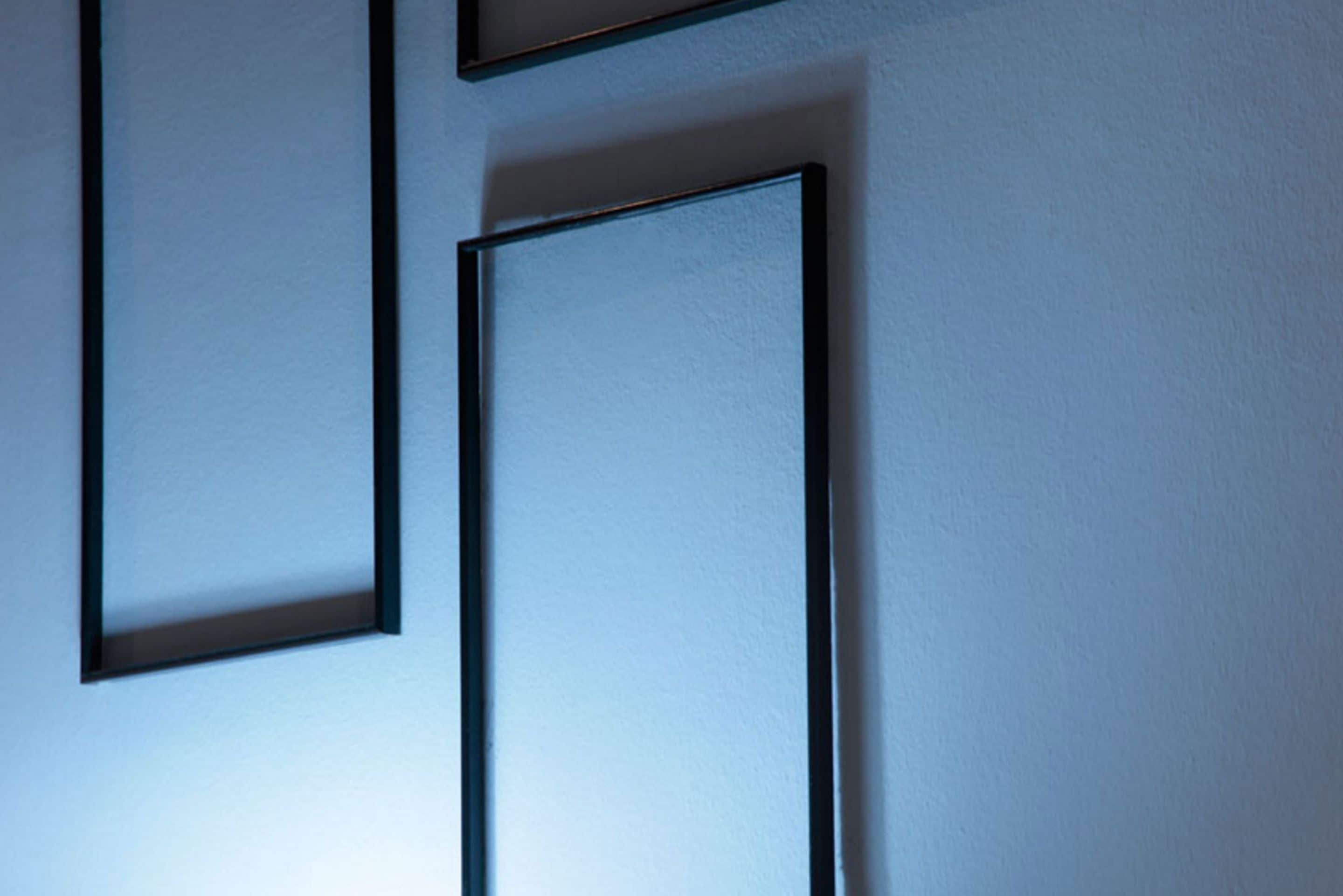 Eine Wand mit drei rechteckigen Bilderrahmen.