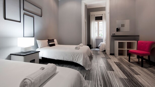 A hotel room with two beds, a desk, a chair, and a vanity with a mirror. - Hostal Boutique Khronos (Barcelona)