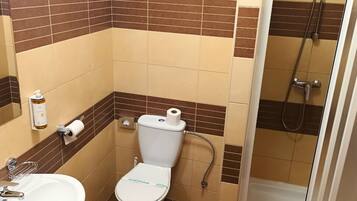 A small bathroom with a toilet, sink, and shower.