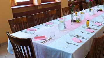 A long dining table set for a meal with chairs around it, a pitcher, and a vase with flowers.