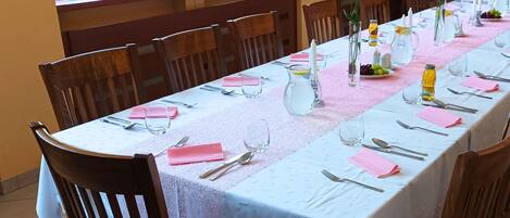 A long dining table set for a meal with chairs around it, a pitcher, and a vase with flowers.