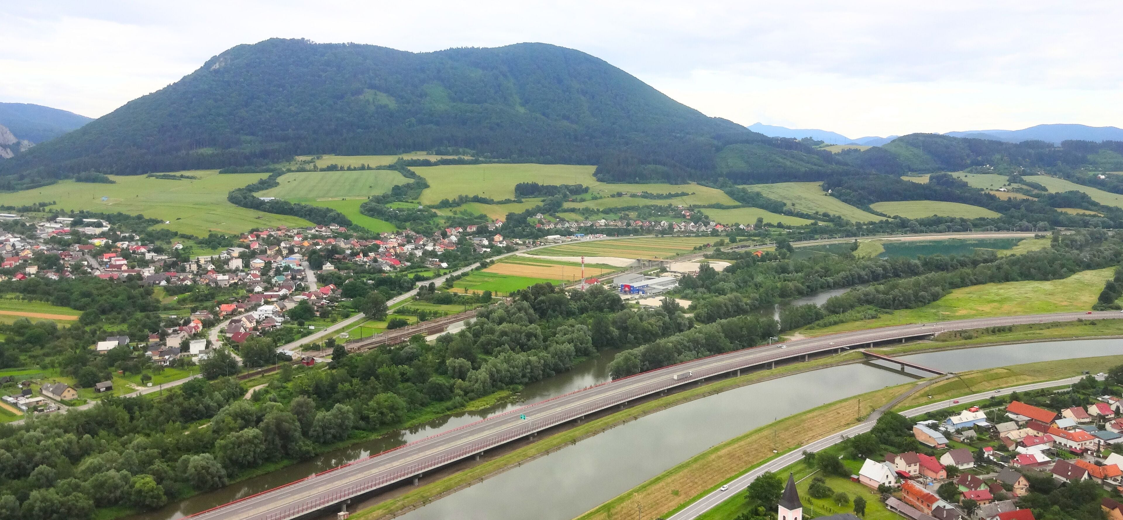 A river running through a town with a bridge and a mountain in the background.