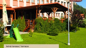 Un hotel con terraza, parque infantil y un cartel que indica el nombre del hotel.