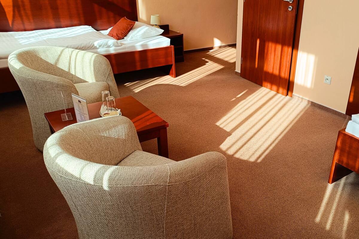 A hotel room with a bed, a chair, a small table, and a nightstand.