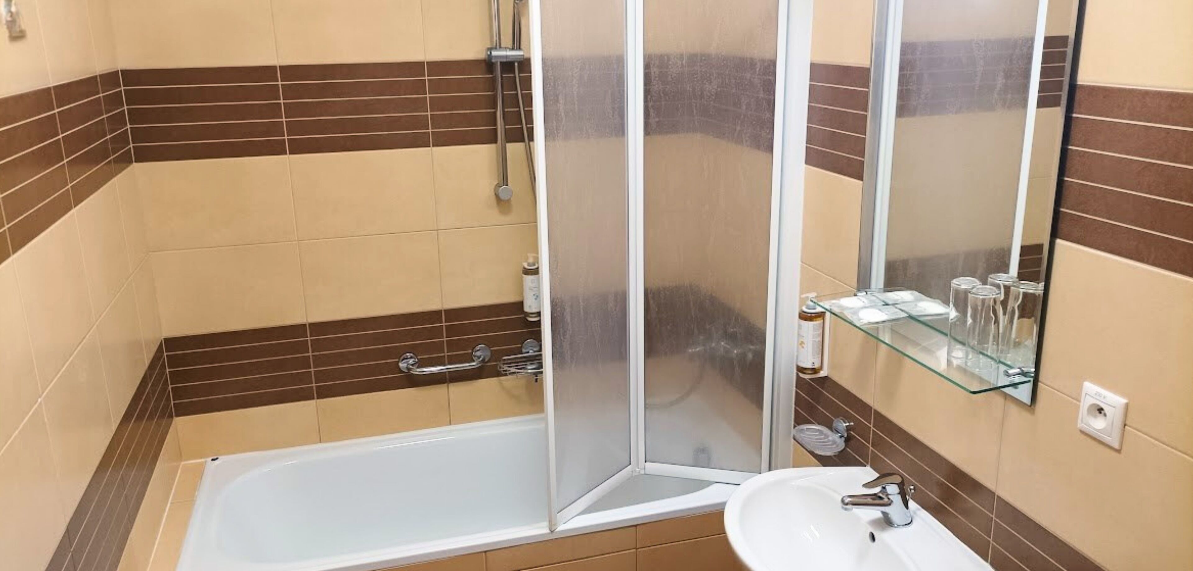 A bathroom with a bathtub, a glass shower enclosure, a sink, and a mirror.
