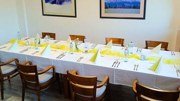 A dining area with a long table set for six, wooden chairs, and framed pictures on the walls.