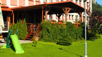 Un hotel con terraza, parque infantil y un cartel que indica el nombre del hotel.