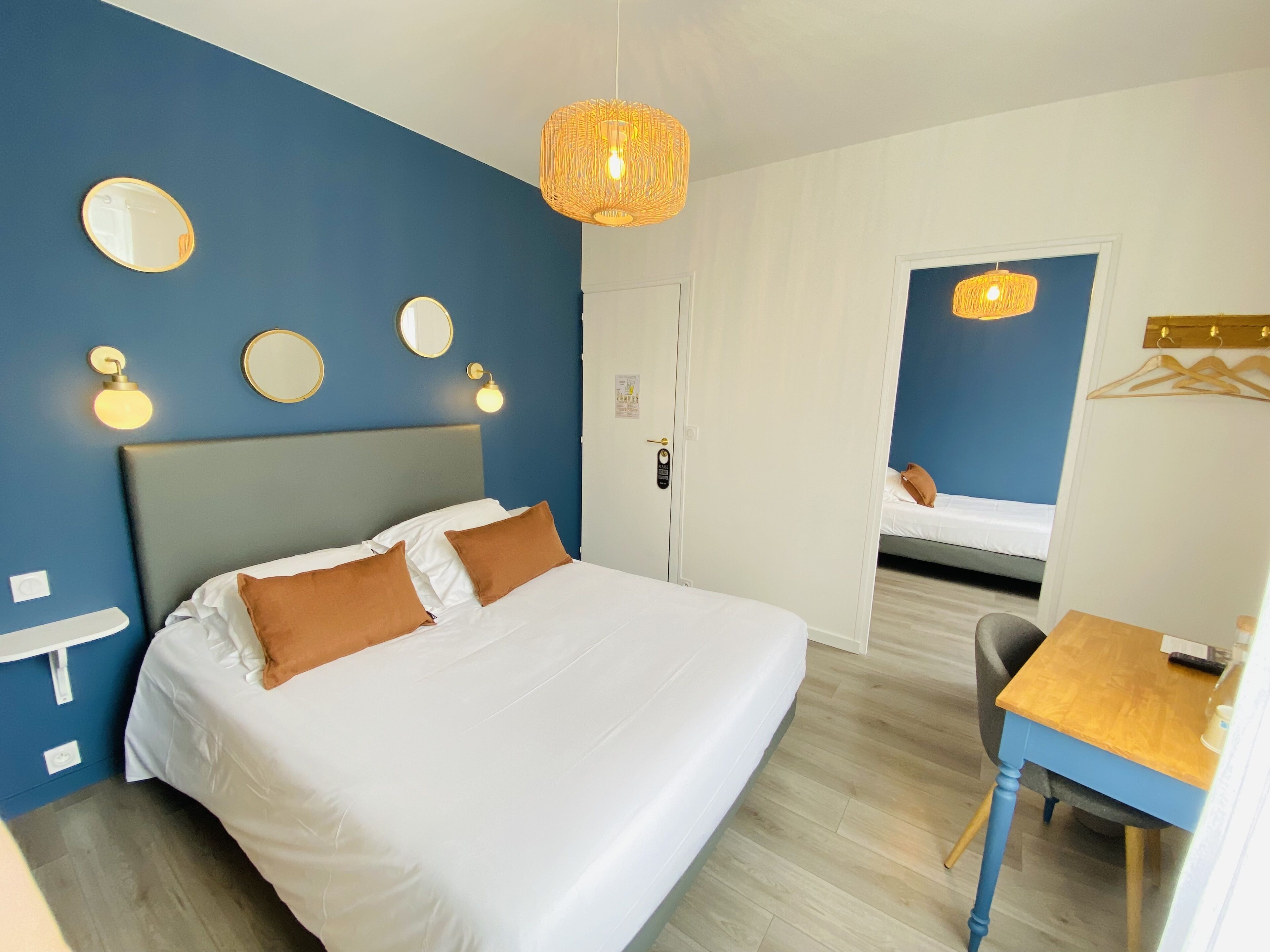 Et hotelværelse med en stor seng, et skrivebord og et spejl.