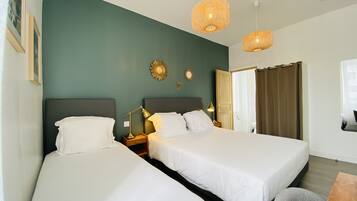 A hotel room with two beds, a wooden nightstand, a desk, and a window with curtains.